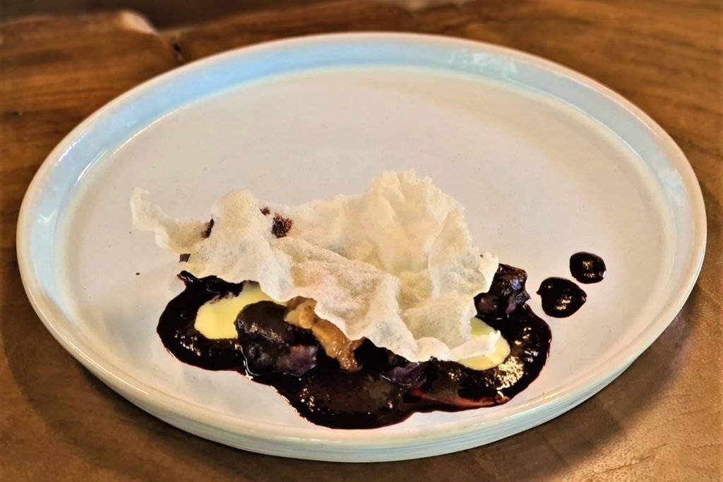 na foto temos um prato branco com nhoque e molho de açaí