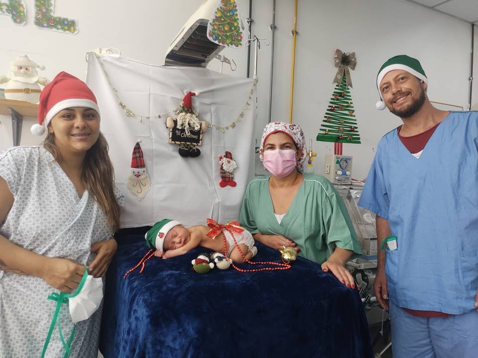 Pais e enfermeira em ensaio fotográfico com bebês-noéis no HUB