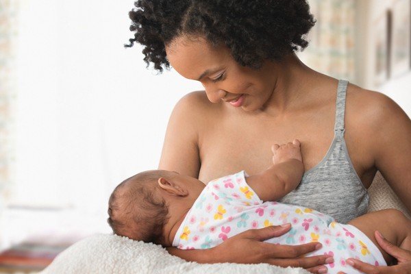 A mother holds a baby in her arms while breastfeeding - Metropolis