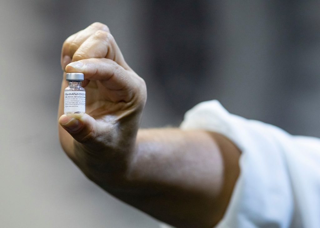 mão segura frasco de vacina contra Covid-19 da Pfizer