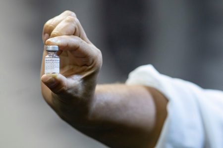 mão segura frasco de vacina contra Covid-19 da Pfizer