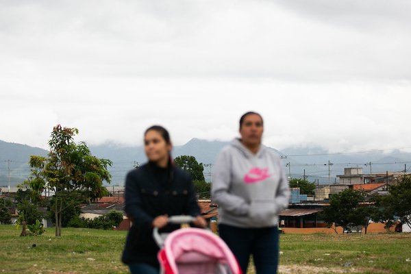 duas mulheres andando uma do lado da outra passeando com um carrinho rosa