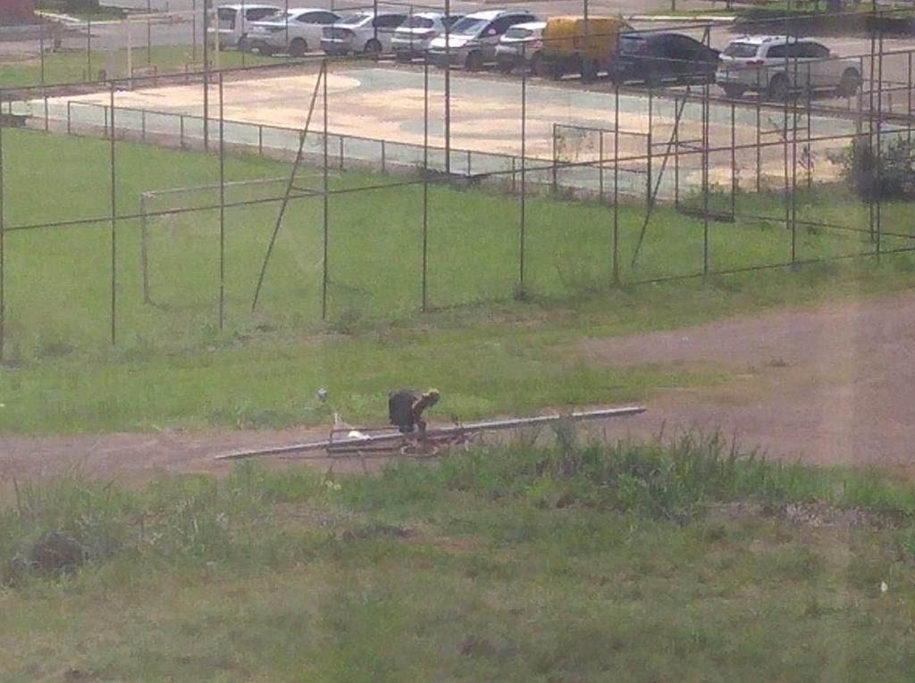 Homem com bicicleta e poste deitado em chão de grama