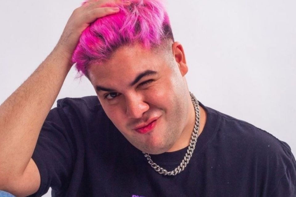 Foto colorida de um homem branco com o cabelo rosa