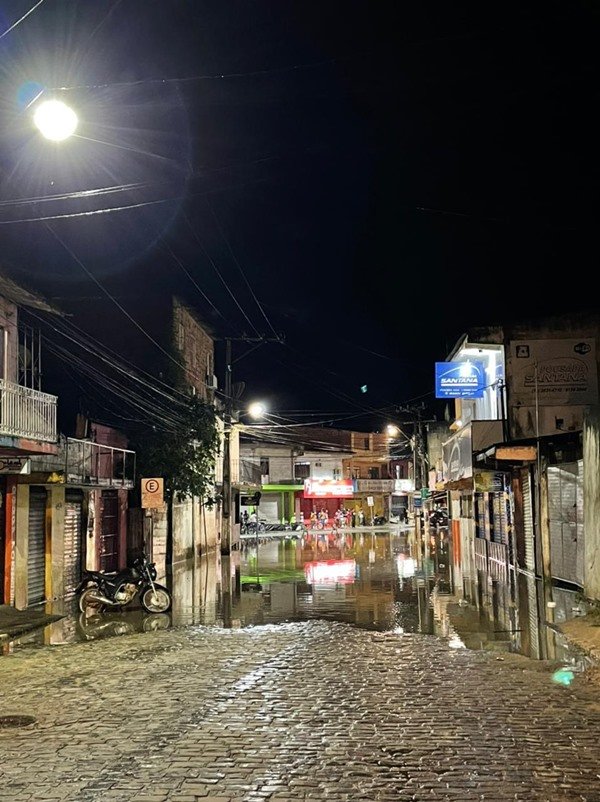 Rua de paralelepípedo com pontos de alagamento entre prédios antigos
