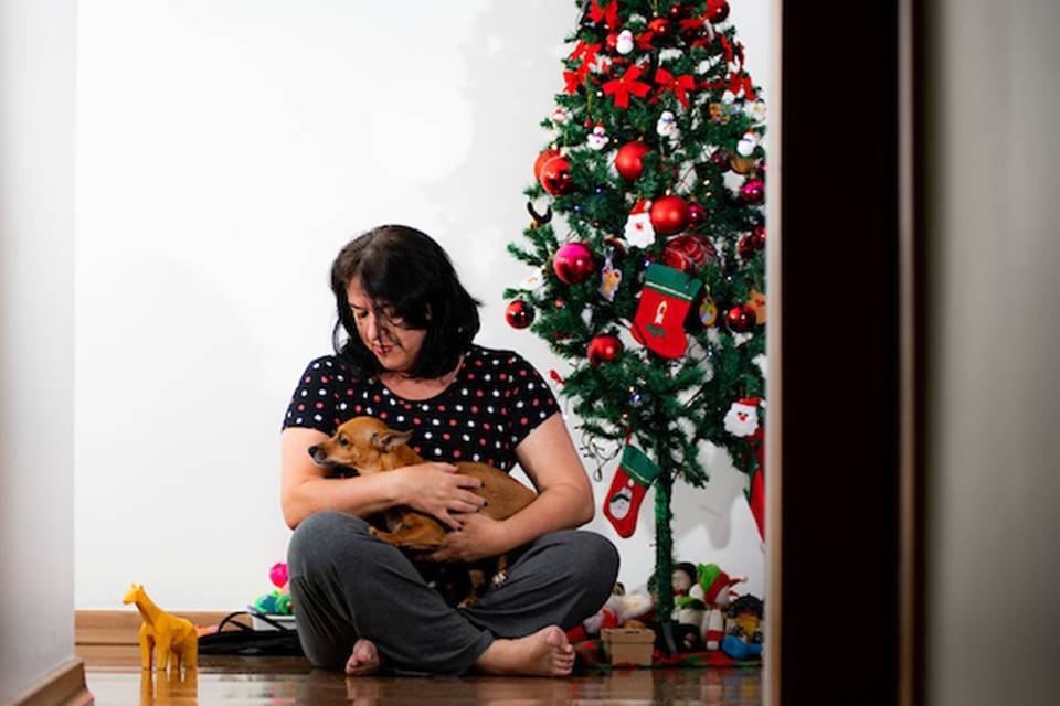 Tutora segurando cachorrinha e árvore de Natal
