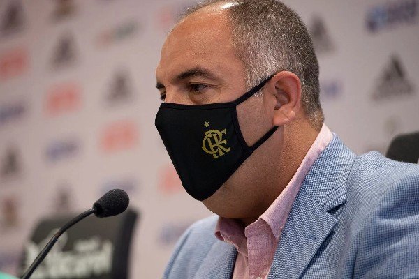 Fotografia colorida de Marcos Braz em coletiva de imprensa com máscara do Flamengo