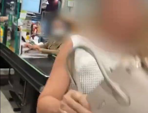 Mulher com bolsa ao lado de caixa de supermercado