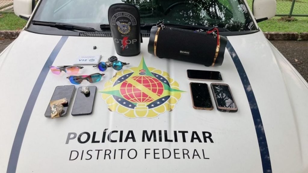 celulares, óculos, caixa bluetooth em cima de capô de carro