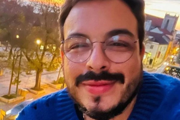 Fotografia colorida de Luis posando para selfie em varanda de prédio