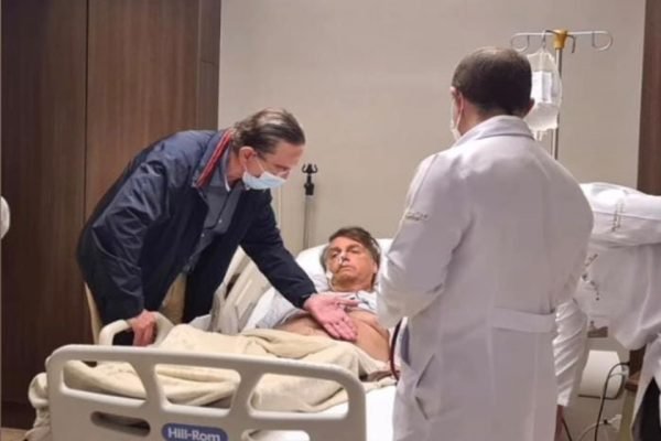 Bolsonaro na cama de hospital sendo examinado por Antônio Luiz Macedo