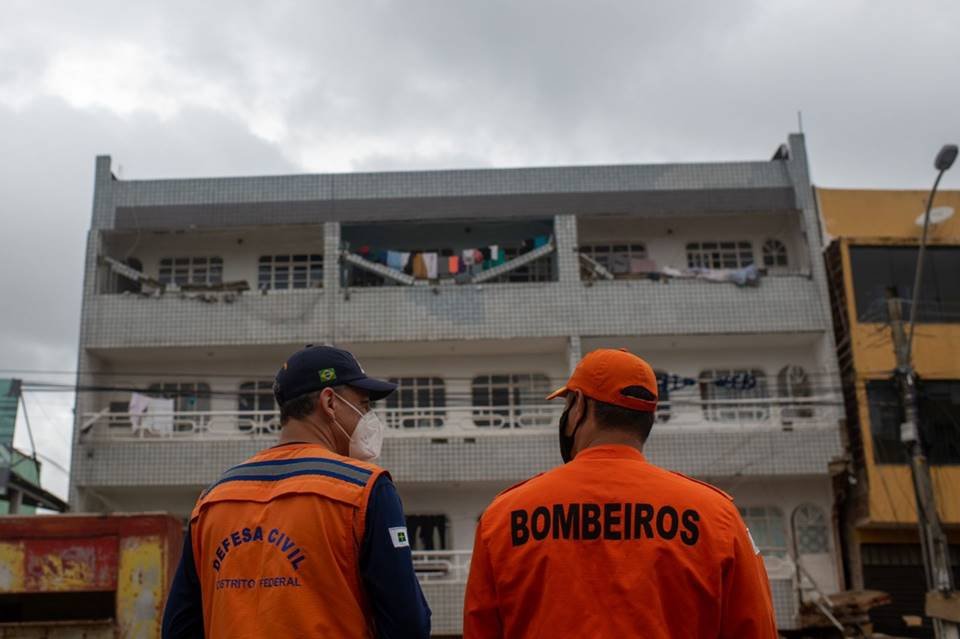Dois homens de laranja diante de prédio