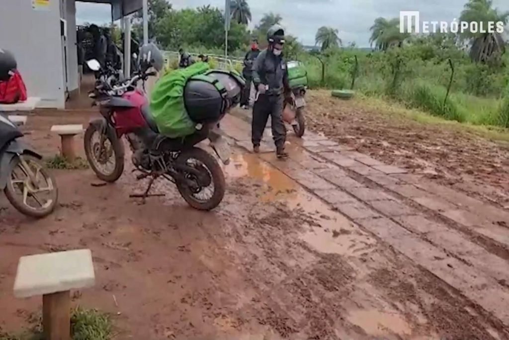 Motoqueiro caminha em meio à lama