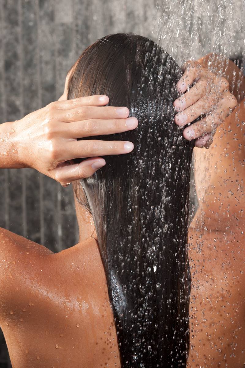 Mulher lavando o cabelo castanho sob o chuveiro