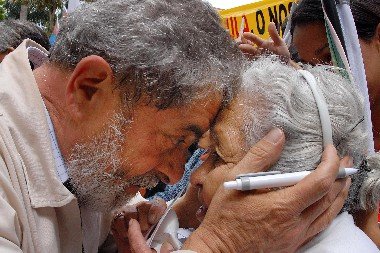 Lula, em meio ao público, segura o rosto de uma senhora na multidão. Eles estão muito próximos e sorriem - Metrópoles
