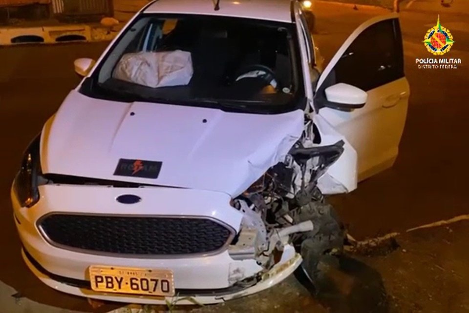 Carro branco com a frente amassada e porta aberta