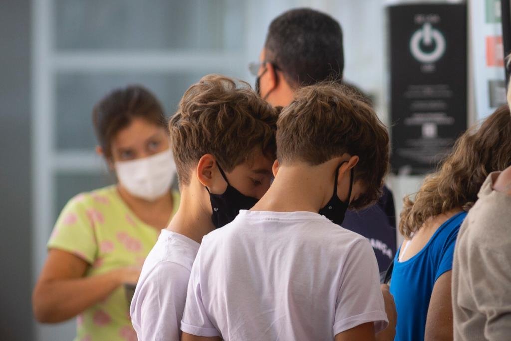 Meninos de camisa branca e máscara preta de costas