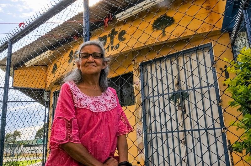 Mulher de óculos e cabelos brancos sorrindo em frente a grade