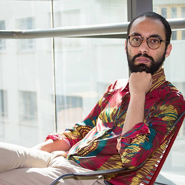 Professor Brunno Almeida Maia sentado com camisa estampada