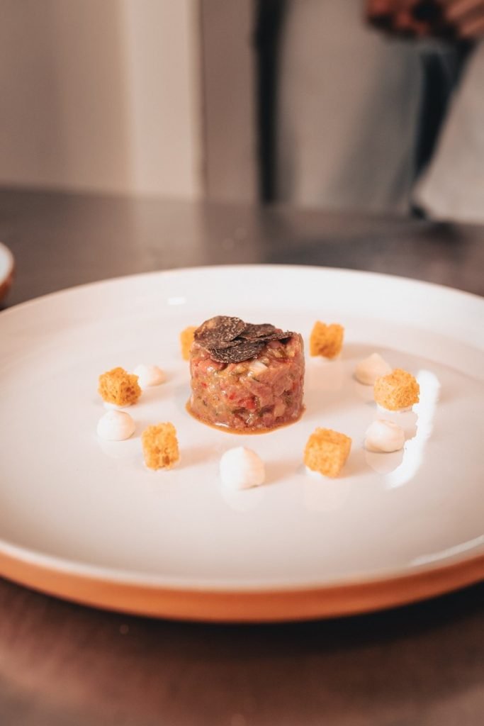 Pequeno montinho de carne crua com decorações em prato branco
