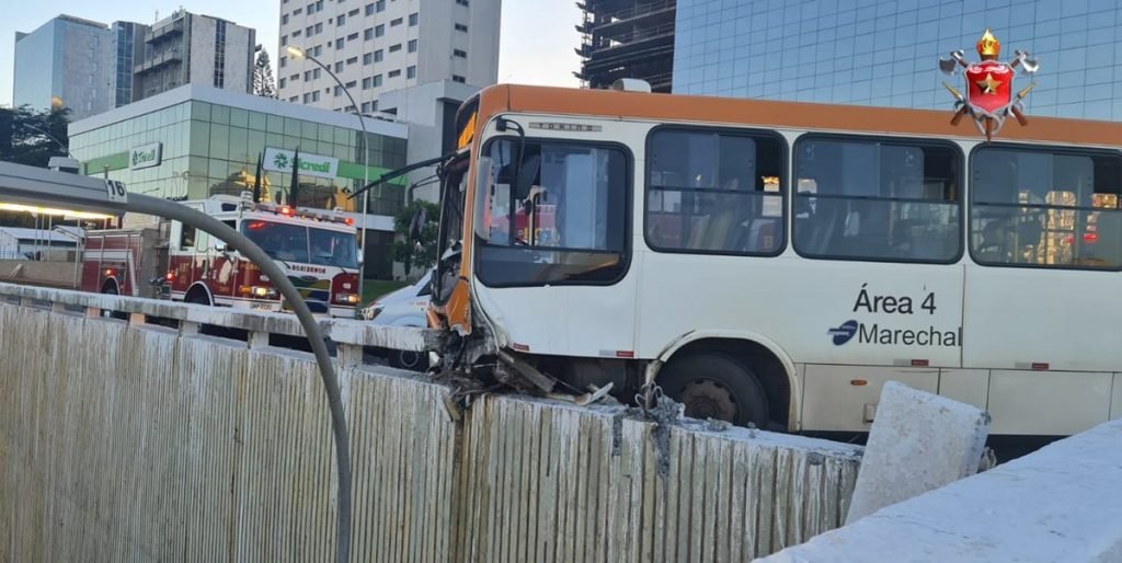 Ônibus branco com laranja batido em muro branco