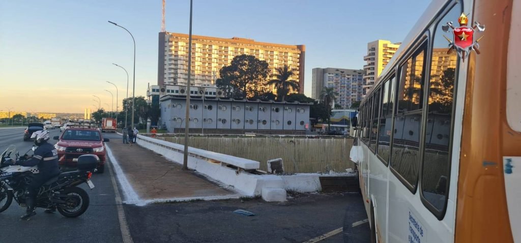 Traseira de ônibus branco com laranja batido em muro branco