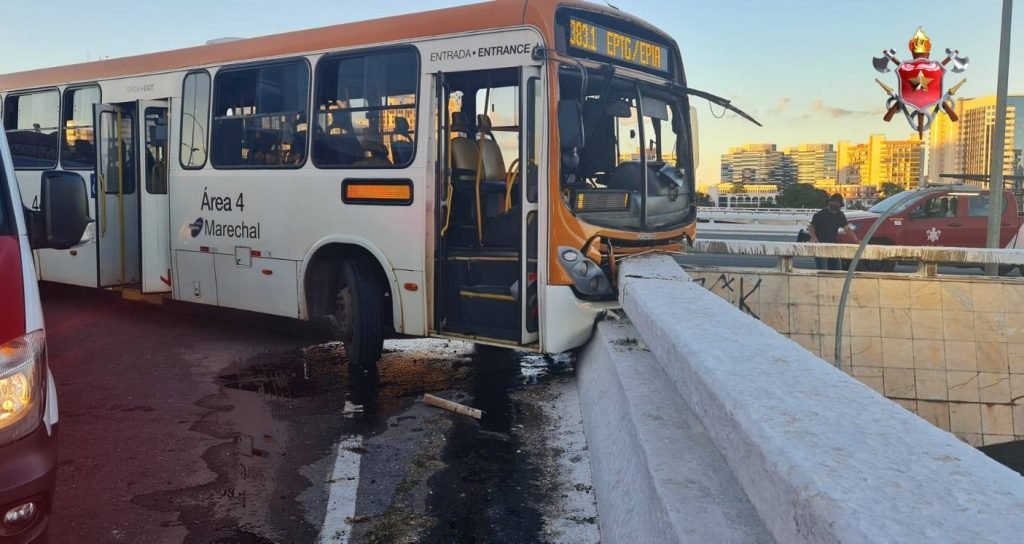 Ônibus branco com laranja batido em muro branco