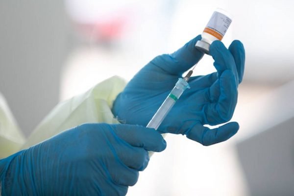 Color photo of a person administering the covid-19 vaccine