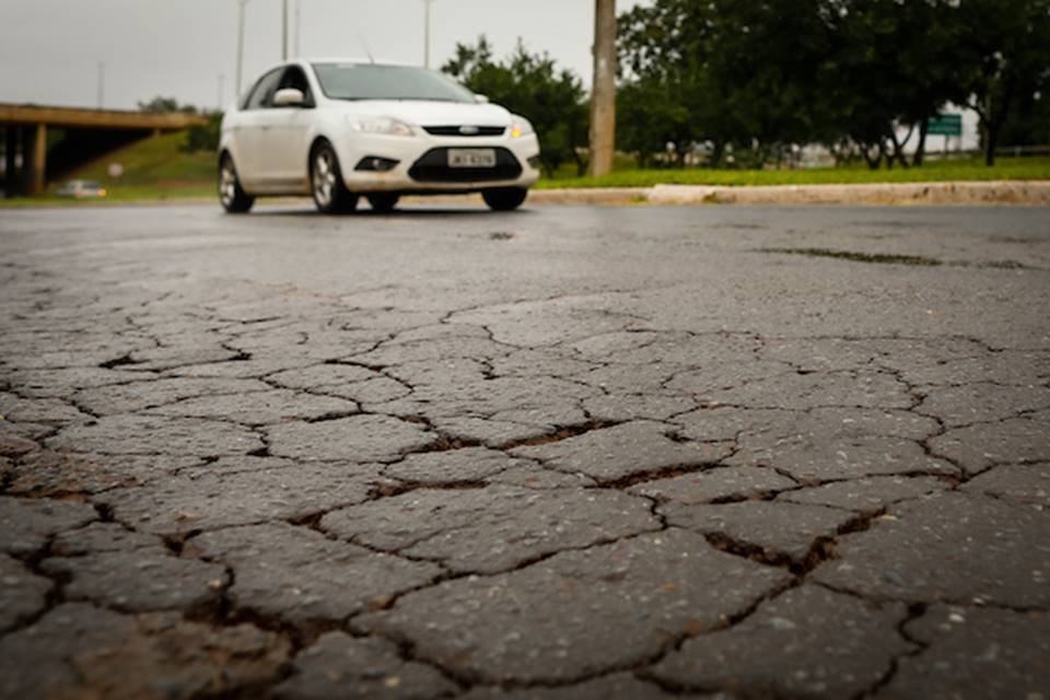 Carro passando por via com asfalto rachado