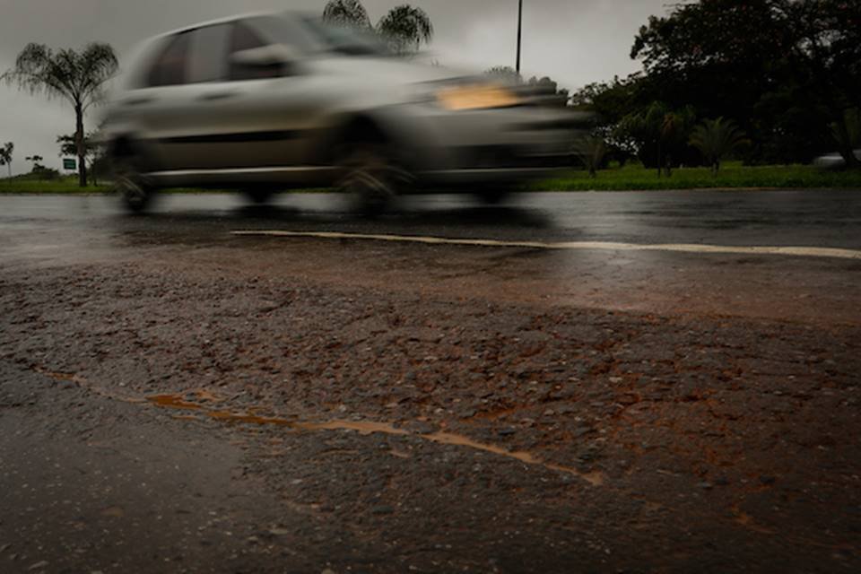 Carro passando por via com asfalto rachado