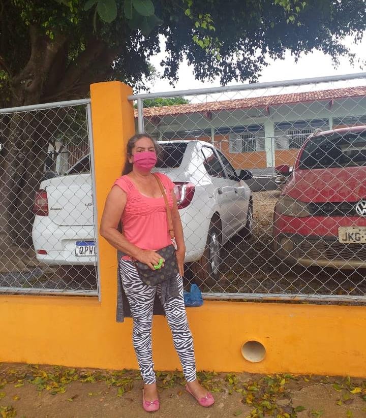 Mulher de calça e blusa rosa em frente a carros estacionados