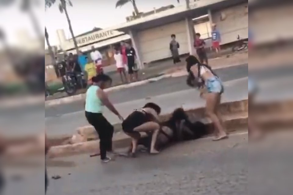 Mulheres brigando em pista de asfalto
