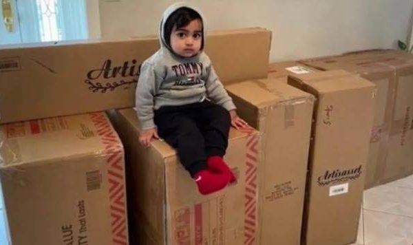 Criança sentada em cima de caixas