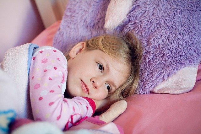 Fotografia colorida de menina deitada na cama