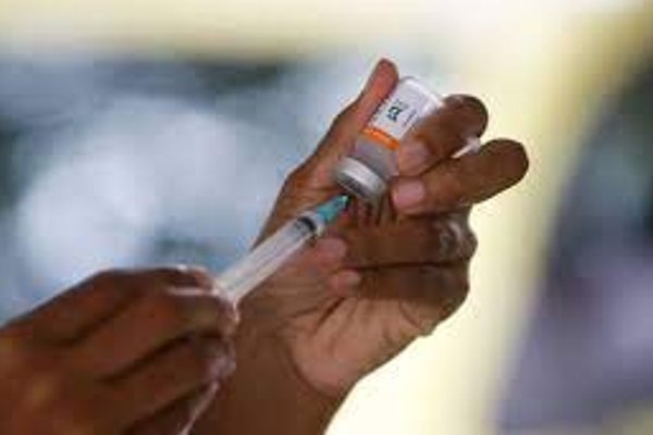 Fotografia de dose de vacina sendo medida na seringa colorida