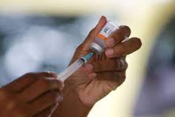 A color photograph of the vaccine dose being measured into a syringe