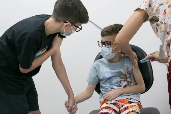 Color photograph of siblings getting vaccinated