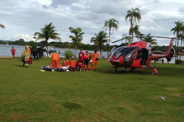 bombeiros tratam pessoa em maca ao lado de helicóptero