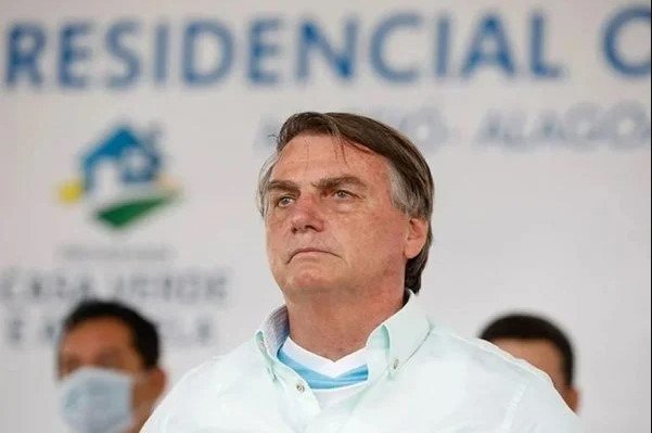 Bolsonaro aprece em evento do governo. Ele usa roupa clara, tem cabelos curtos e olha seriamente para frente - Metrópoles