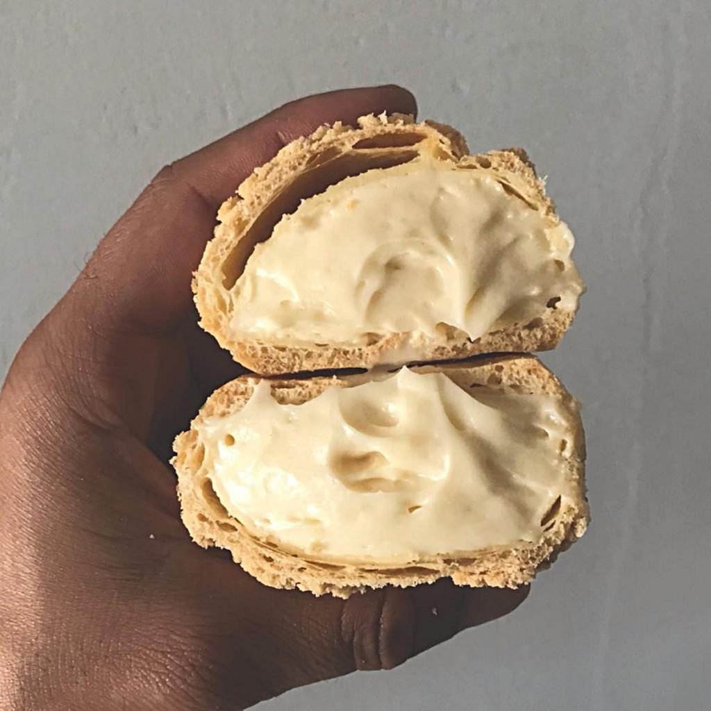 na foto uma mao segura uma massa recheada de creme branco