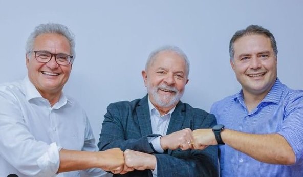 Foto com Renan Calheiros, senador de Alagoas pelo MDB, o ex-presidente Lula (PT) e Renan Filho, governador de Alagoas também do MDB.. Os três sorriem e encostam as mãos, lado a lado, e usam roupas sociais sob um fundo azulado - Metrópoles