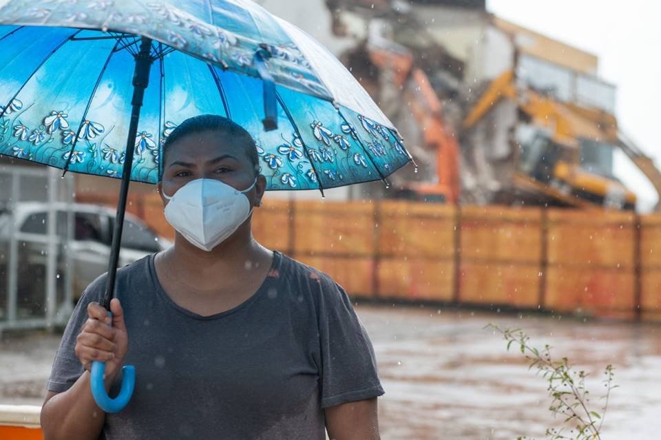 Mulher com guarda-chuva azul e máscara protetora no rosto