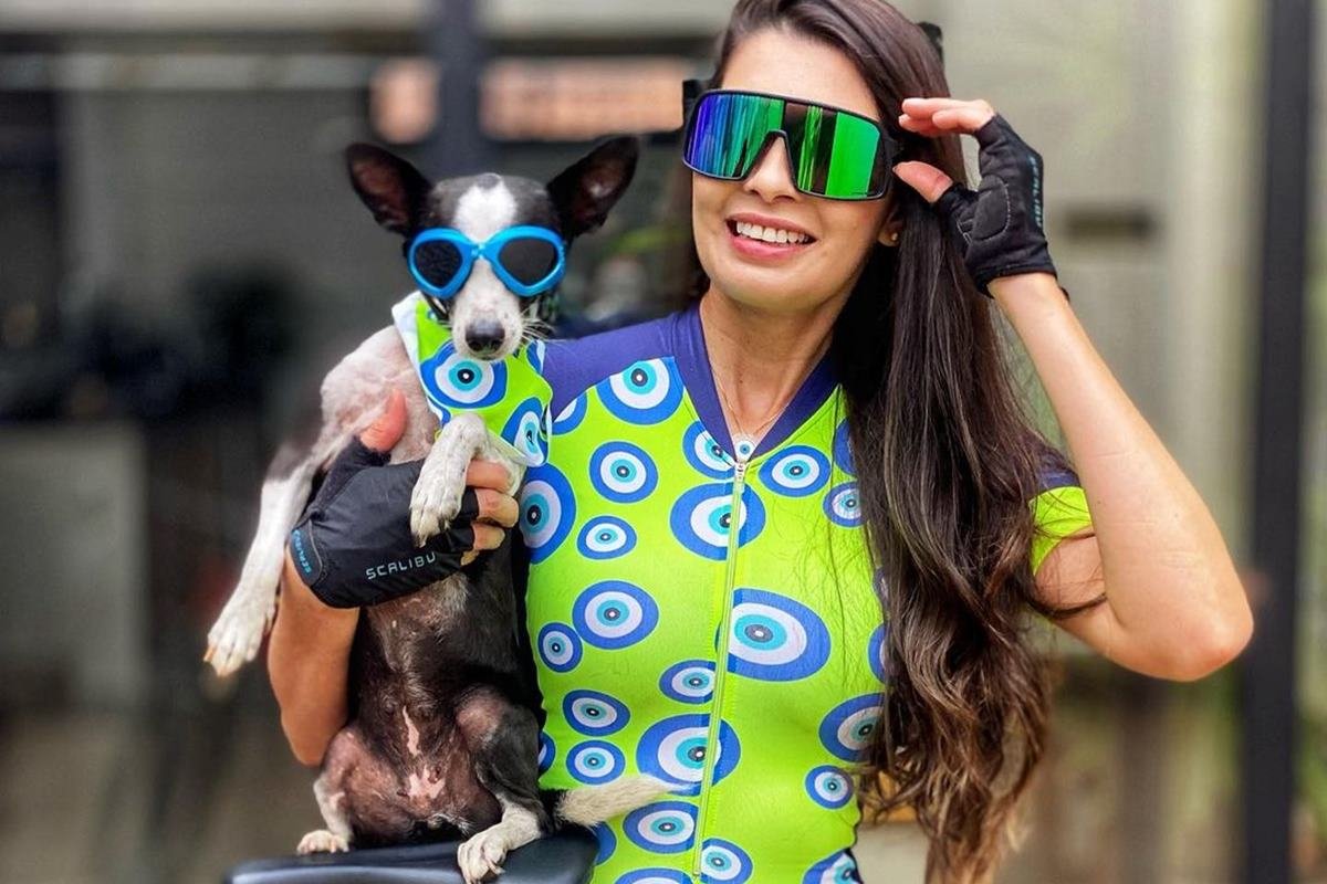 mulher com roupa e óculos de atletismo segurando cachorra com oculos e lenço