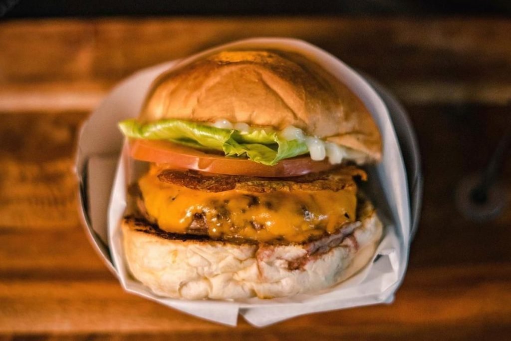 Na foto, vemos um hamburguer com queijo, carne, alface, tomate e maionese - Metrópoles