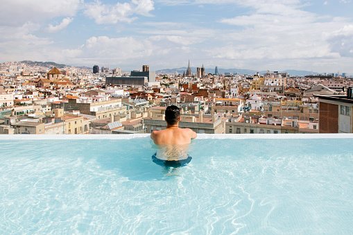 homem em piscina com vista para a cidade