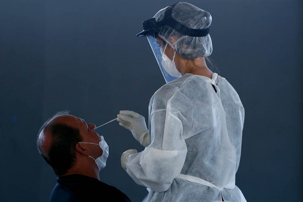 Imagem colorida mostra pessoa sendo submetida a teste Covid por agente de saúde - Metrópoles