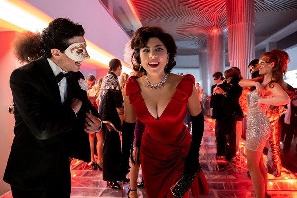 Lady Gaga no filme Casa Gucci. A cena da foto se passa numa pista de dança, em uma festa, com a atriz usando um vestido vermelho e joias da marca Bulgari