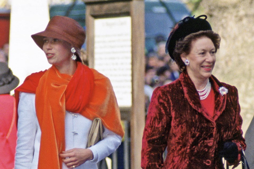 Mulher de chapéu e echarpe laranja ao lado de mulher com chapéu e casaco