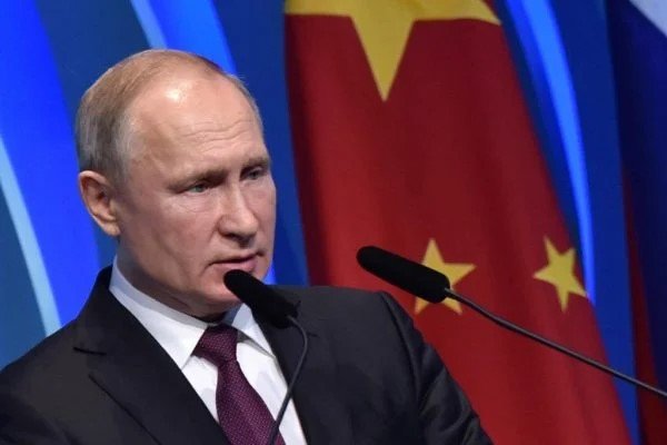 Bajo un fondo azul con una parte de la bandera china, el presidente ruso, Vladimir Putin, hablando en un evento.  Hay dos micrófonos frente a ti - Metropolis