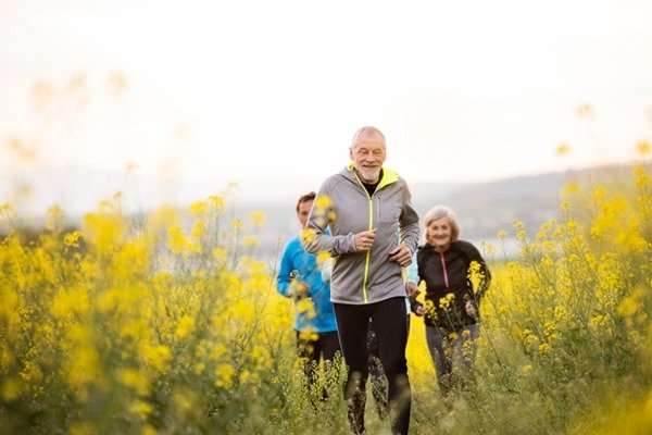 In the color image, people are running in a field. They are wearing long pants and smiling at the floor.